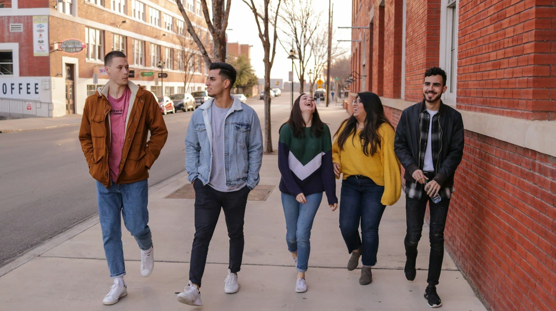 Five students walking together along a city street