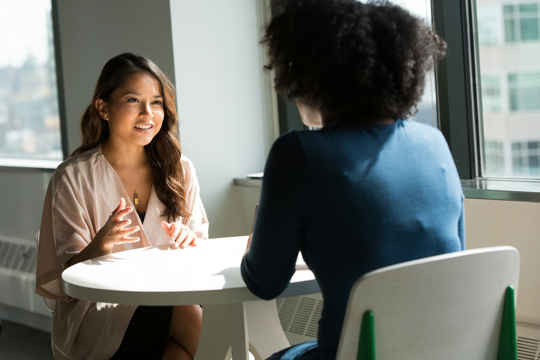 Two people in conversation at a table by a window