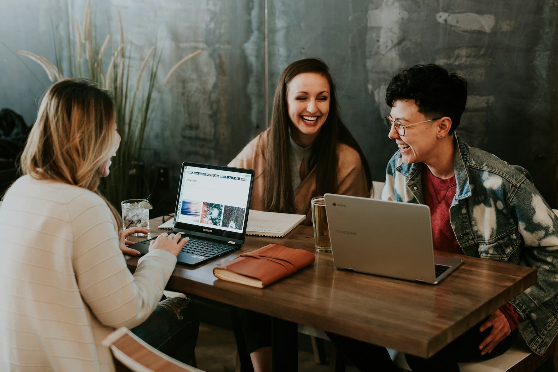 Three people working together around a table with laptops